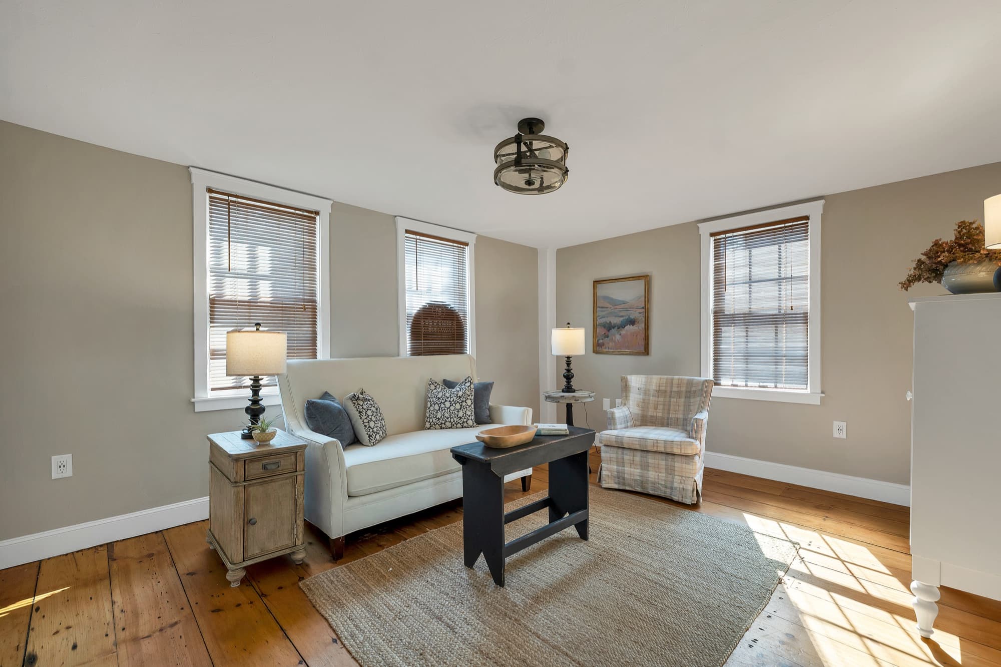 Staged living room with wide-plank hardwood floors and sunlit windows