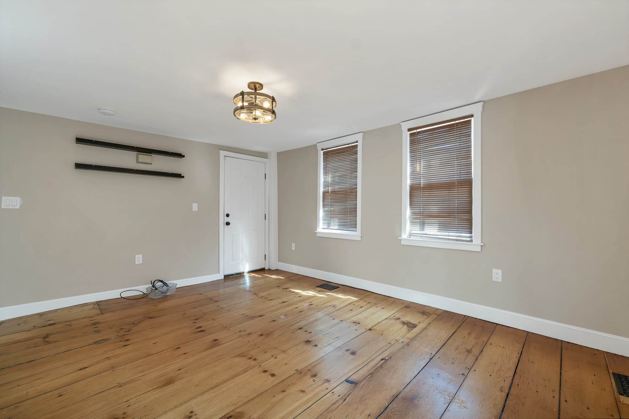 Living room with hardwood floors, a front door, and bright windows