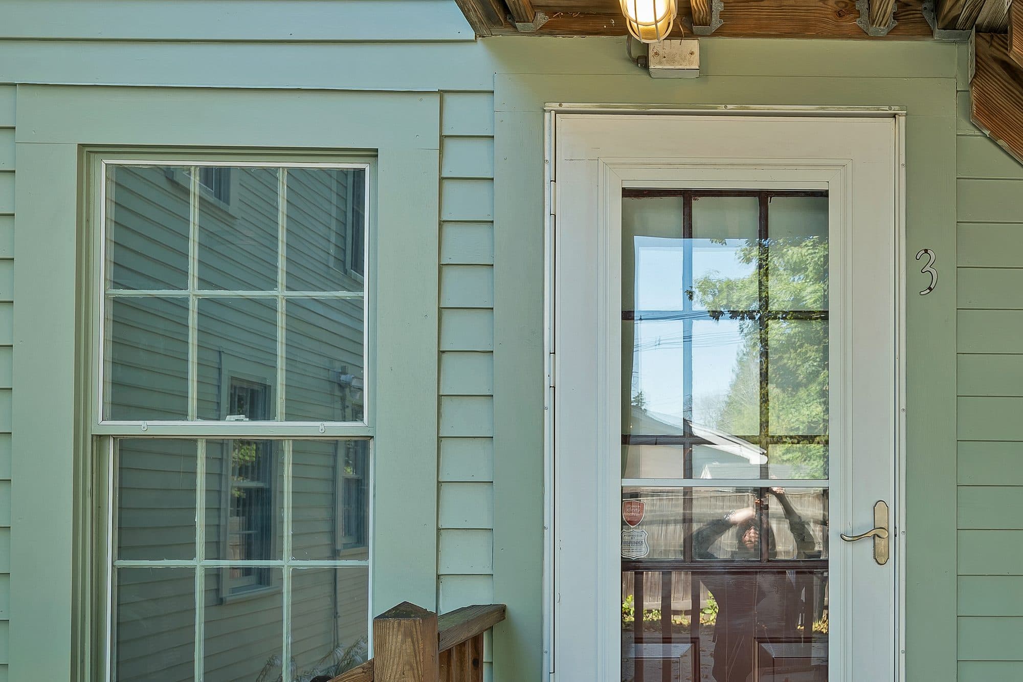 The Unit 3 entry door off the rear porch, freshly painted sage green siding